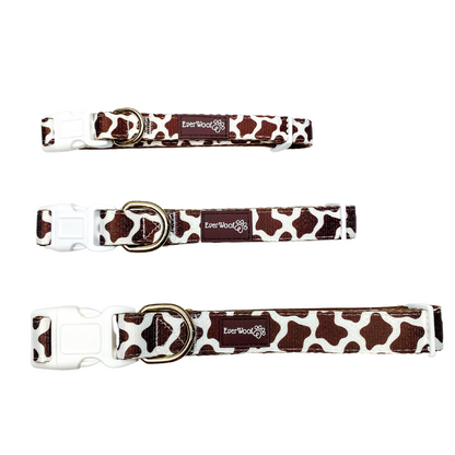 Three cow print dog collars with gold buckles on a white background
