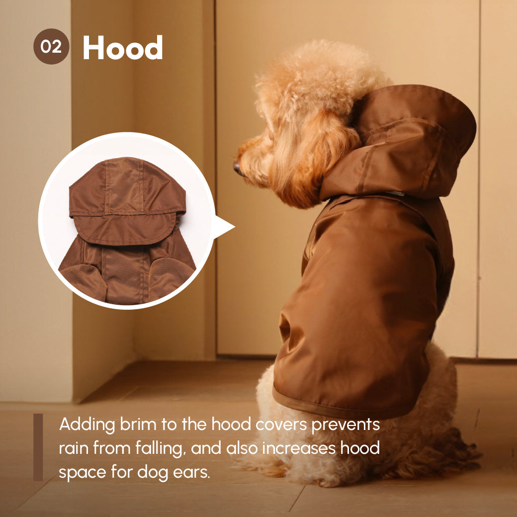 Dog wearing a brown raincoat with a hood, sitting indoors.